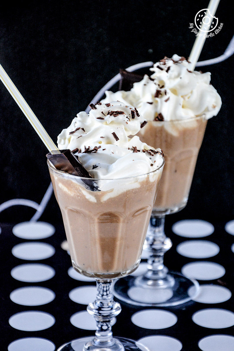 two glasses of banana coffee shake with chocolate toppings on a table