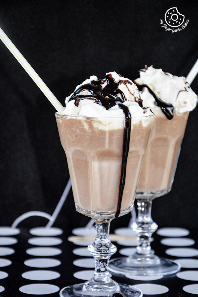 two glasses of banana coffee shake with chocolate sauce and whipped cream