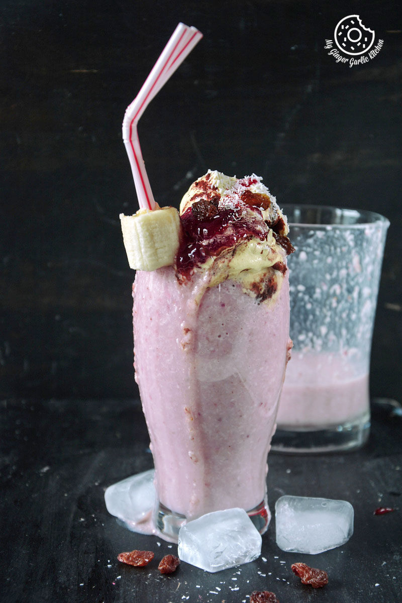 a pink banana raspberry coconut smoothie with a banana and a straw