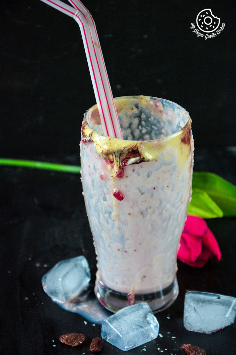 an empty glass of banana raspberry coconut smoothie with a straw and a flower