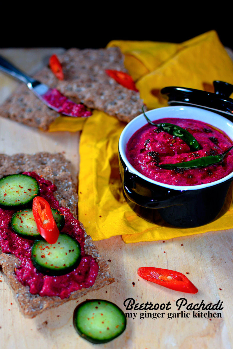 a bowl of kerala style beetroot pachadi with some cucumbers and crackers
