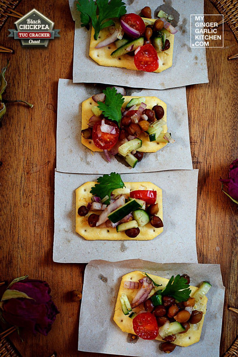 four small crackers with black chickpea tuc cracker chaat on a wooden tray with flowers