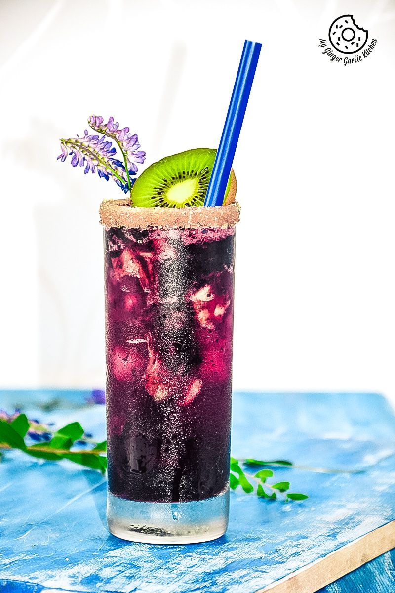 a blueberry kiwi cooler drink with a kiwi and a blue straw