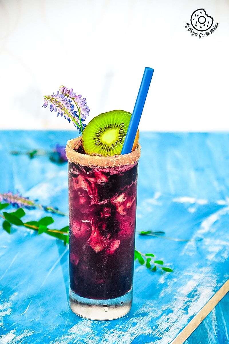 a blueberry kiwi cooler with a kiwi and a straw in it
