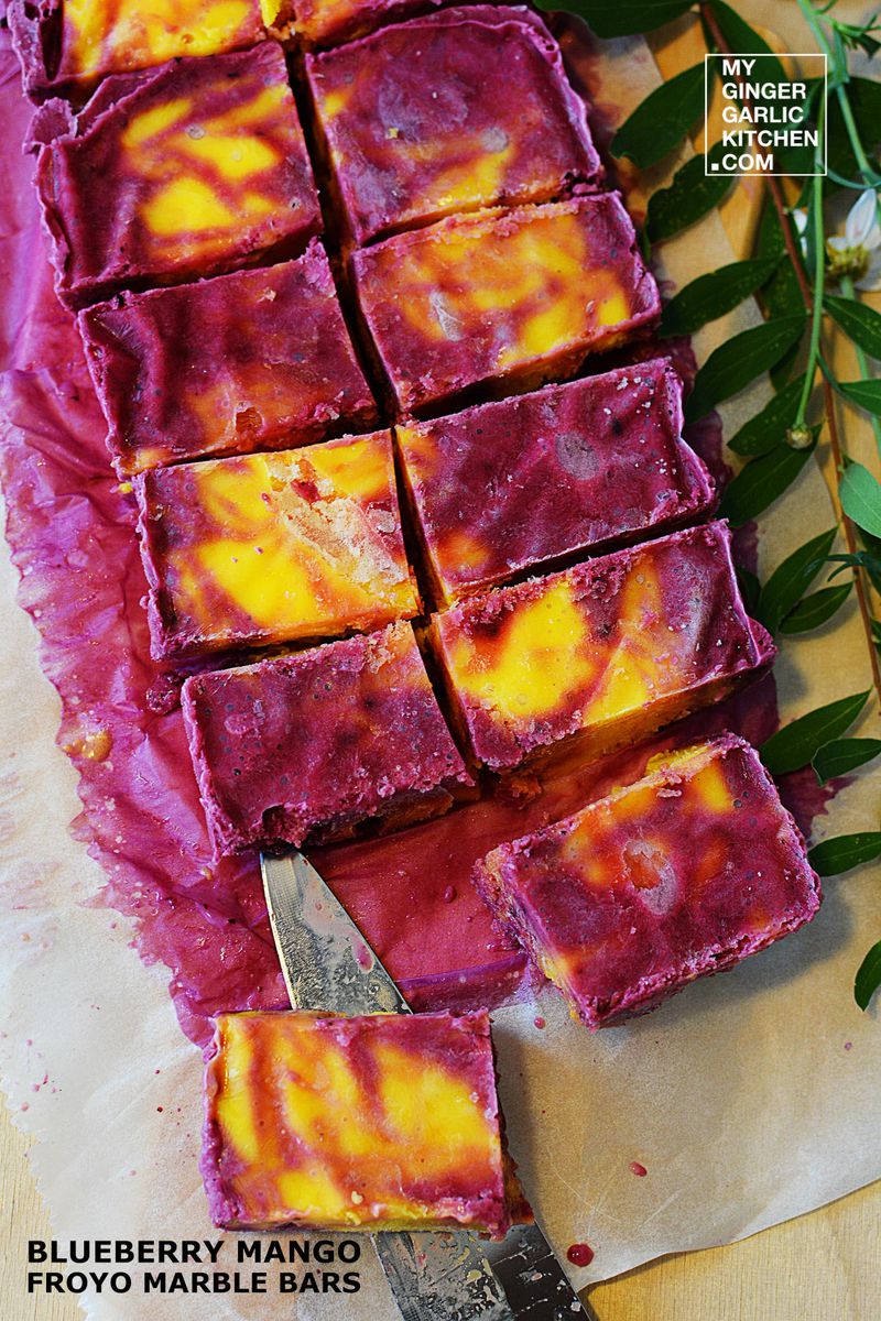 a cutting board with a bunch of blueberry mango froyo marble bars