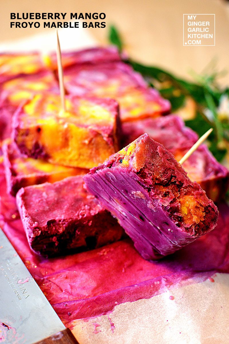 purple and yellow blueberry mango froyo marble bars on a cutting board with a knife