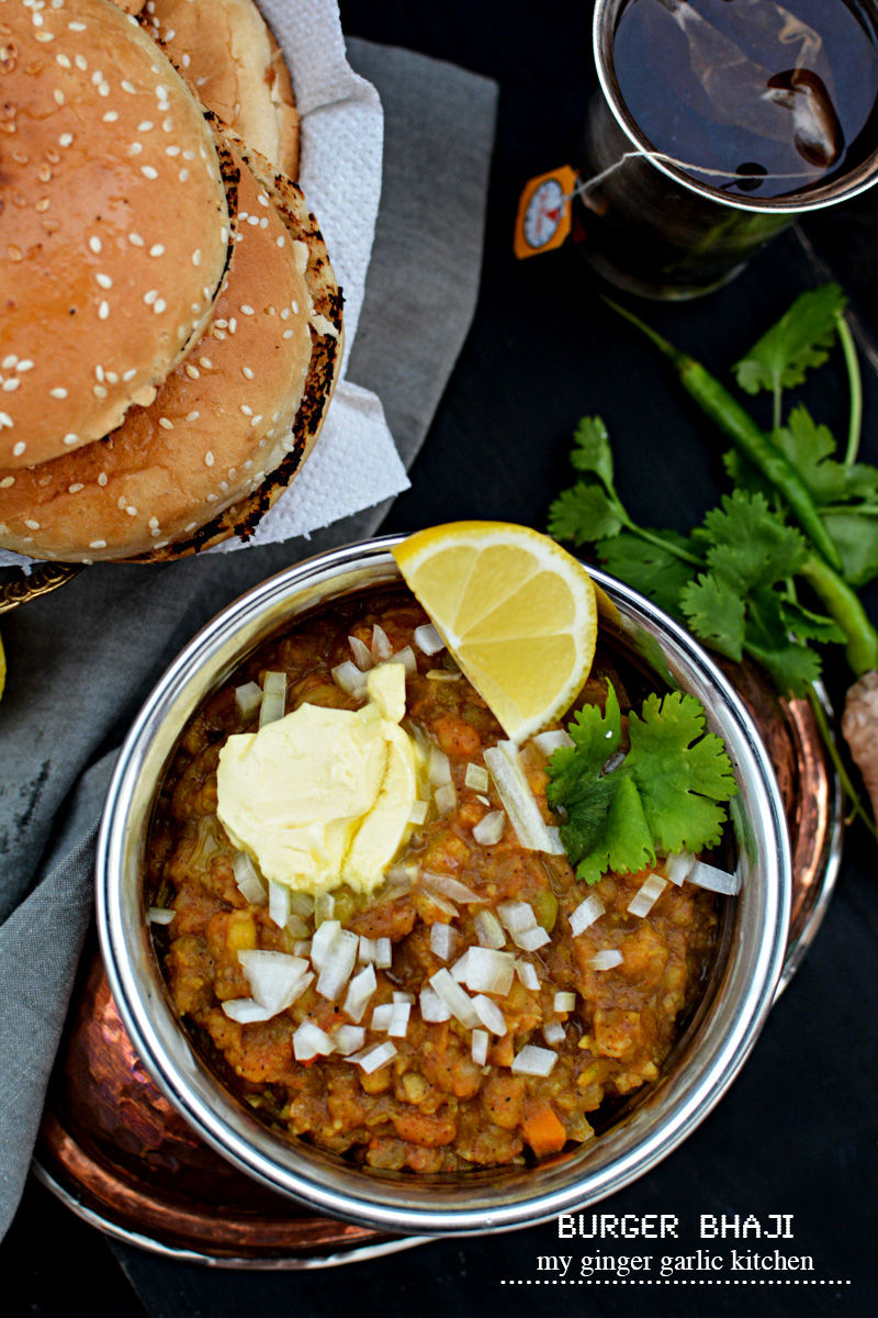 a hamburger and a bowl of bhaji on a table