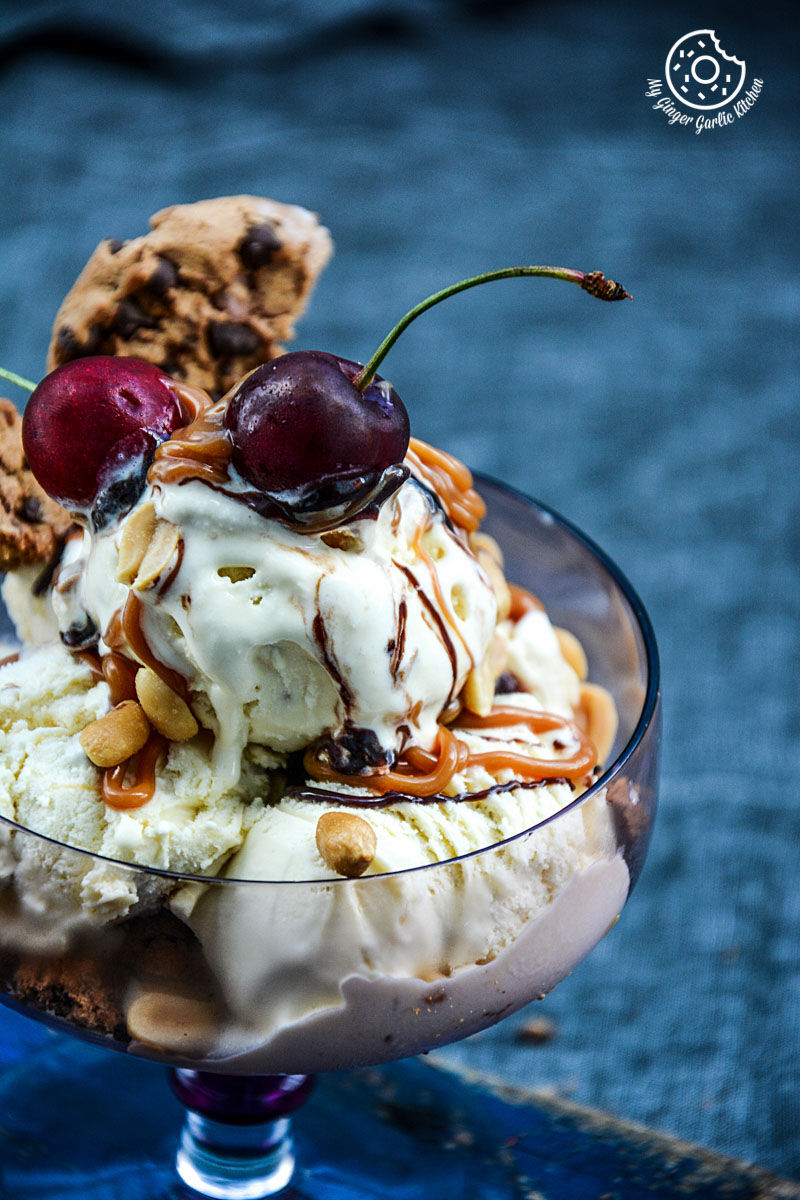 a ice cream sundae in a glass with caramel chocolate chip cookies salted peanuts a cherry on top