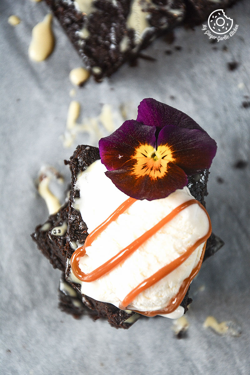 chocolate carrot brownies topped with ice cream, caramel sauce with a flower on top of it