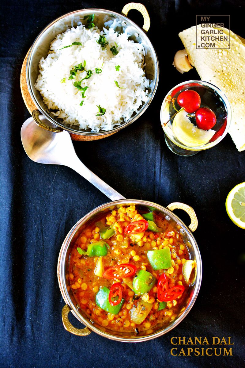 a bowl of rice and a chana dal capsicum curry with roasted papad on the side