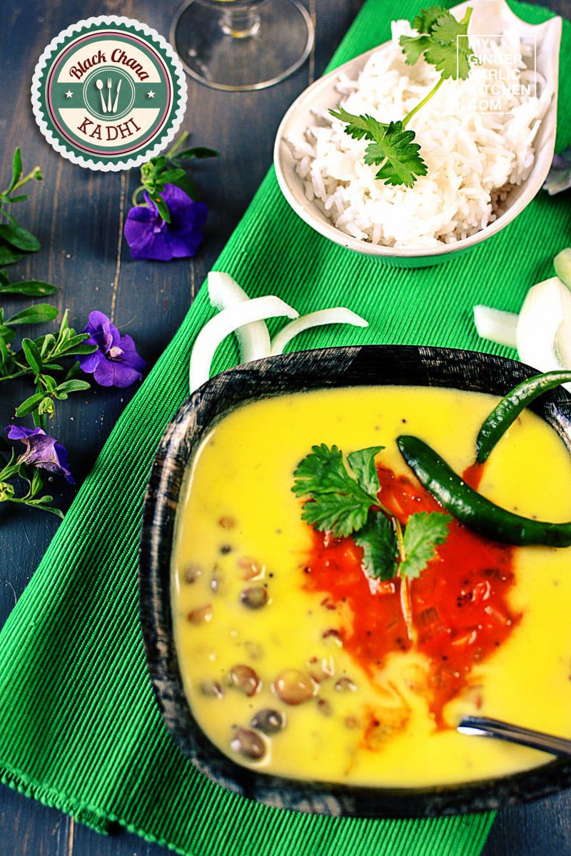 a bowl of chana kadhi with a green chilies and a bowl of rice