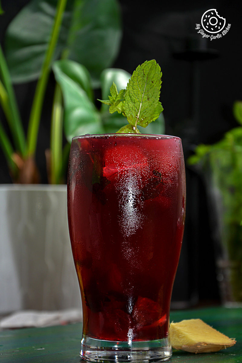 a glass of cherry iced tea with a sprig of mint on top