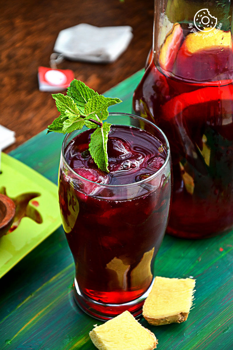 a glass of cherry iced tea with lemon mint ginger and honey with a mint leaf