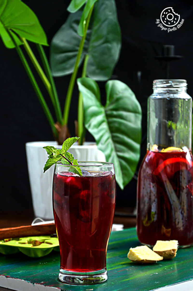 a glass of cherry iced tea with lemon mint ginger and honey with a sprig of mint