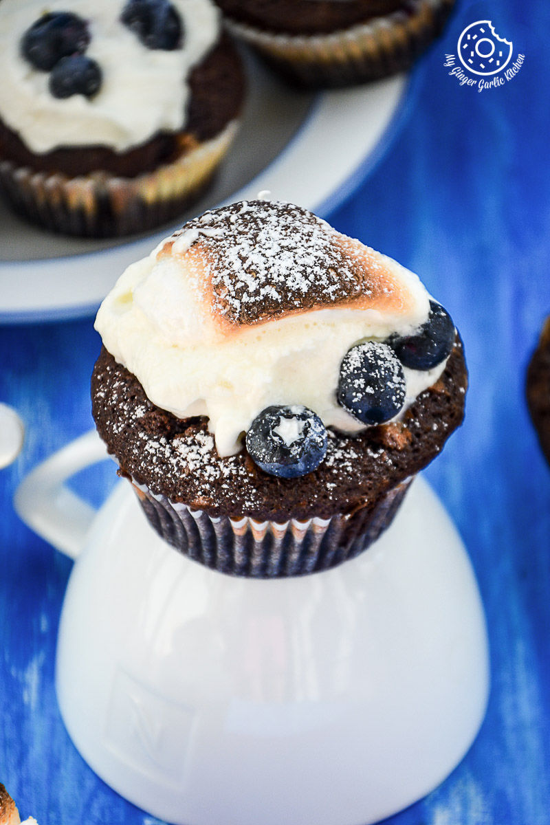 a chocolate cream cheese muffin with blueberries and marshmallow cream on top