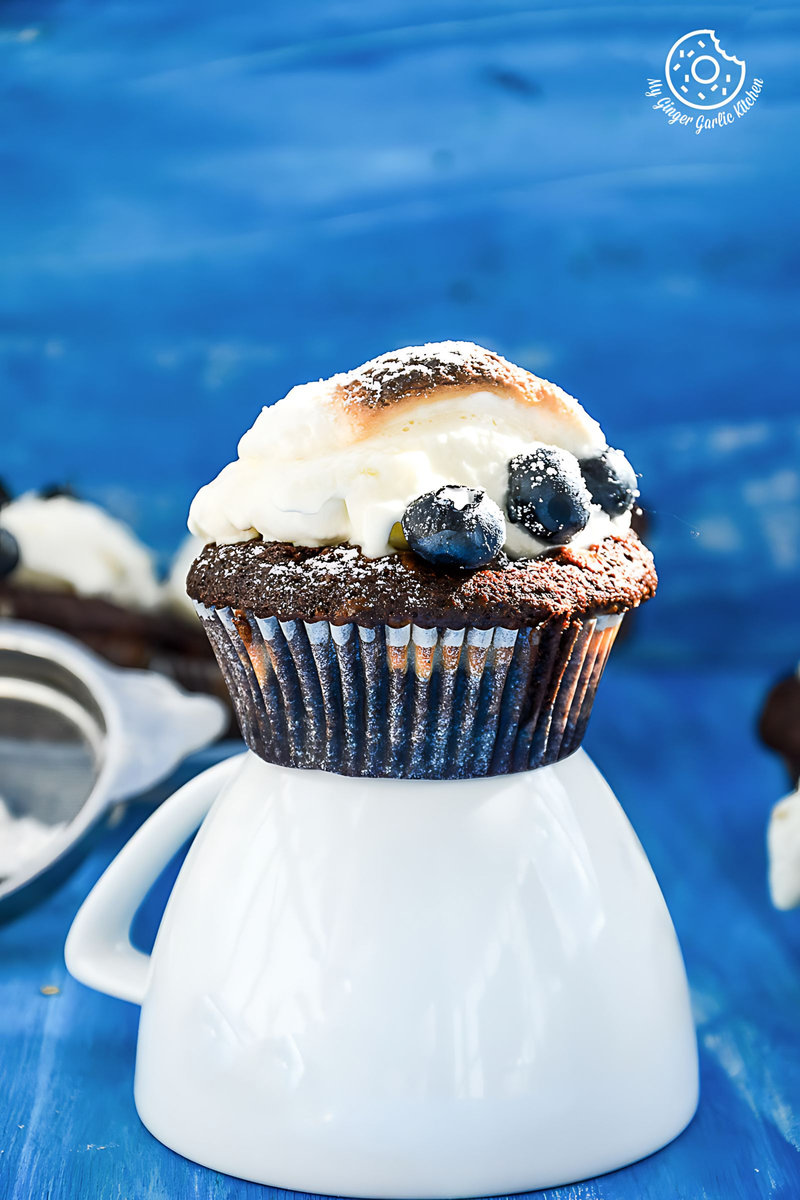 a chocolate cream cheese muffin with blueberries and marshmallow cream on top of it