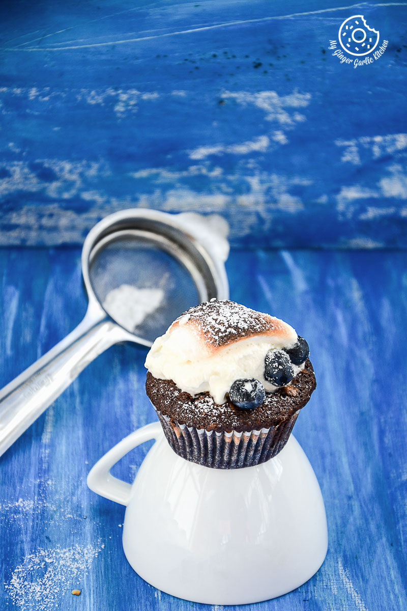 a chocolate cream cheese muffin with blueberries with a frosting on top of it