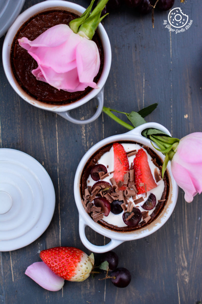 two bowls of chocolate pots de creme with strawberries and cherries