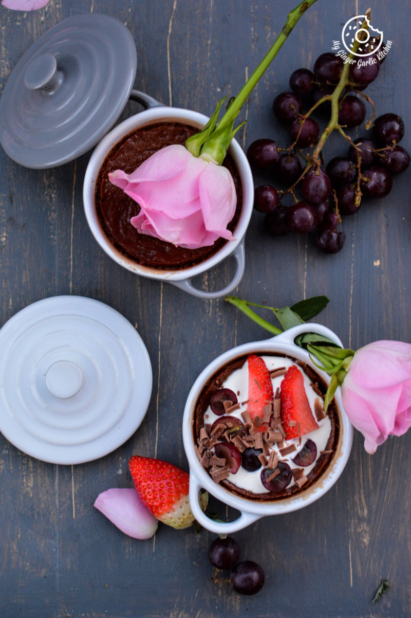 two bowls of chocolate pots de creme with strawberries and a rose