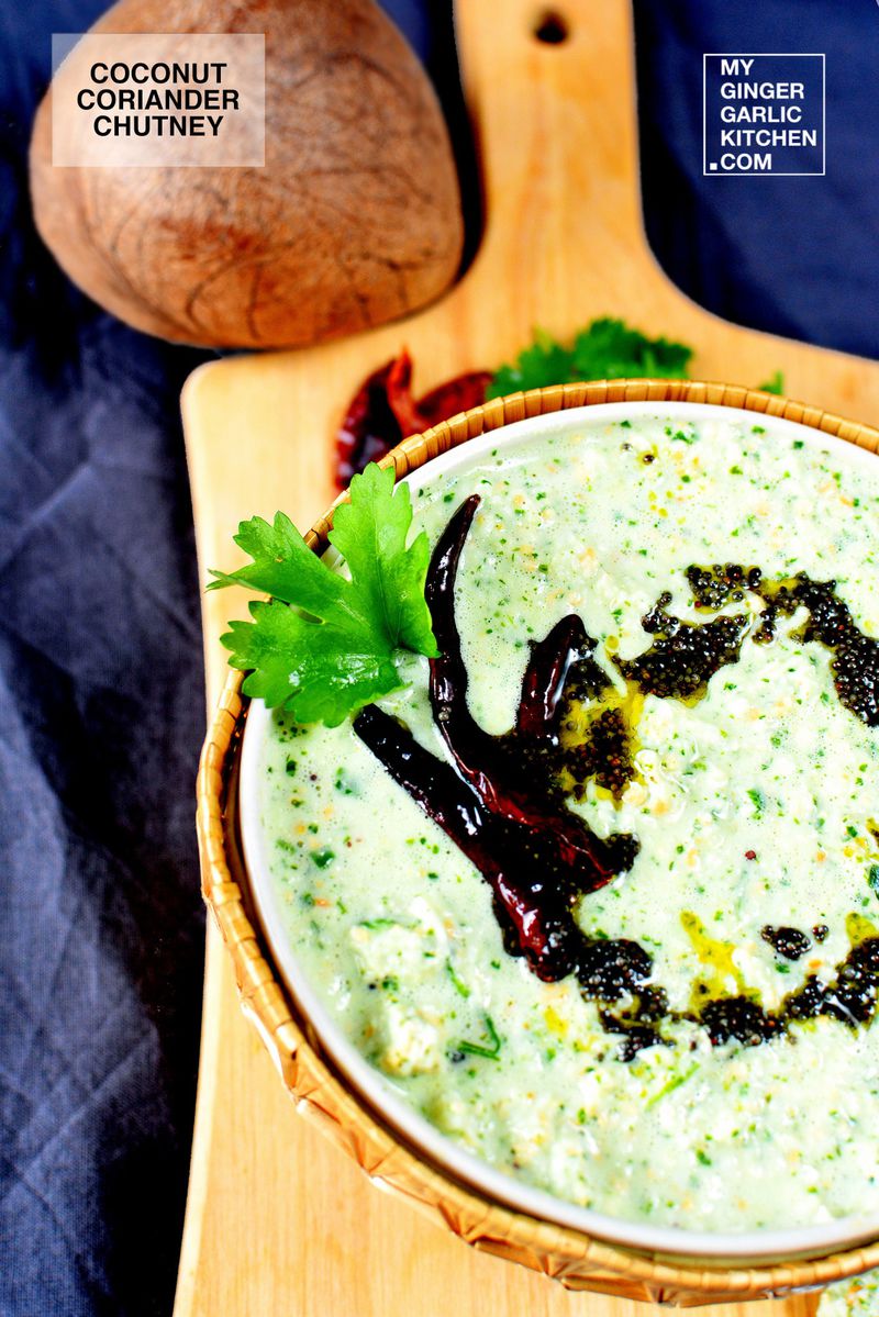 a bowl of coconut coriander chutney with tempering and dried red chilies on a cutting board