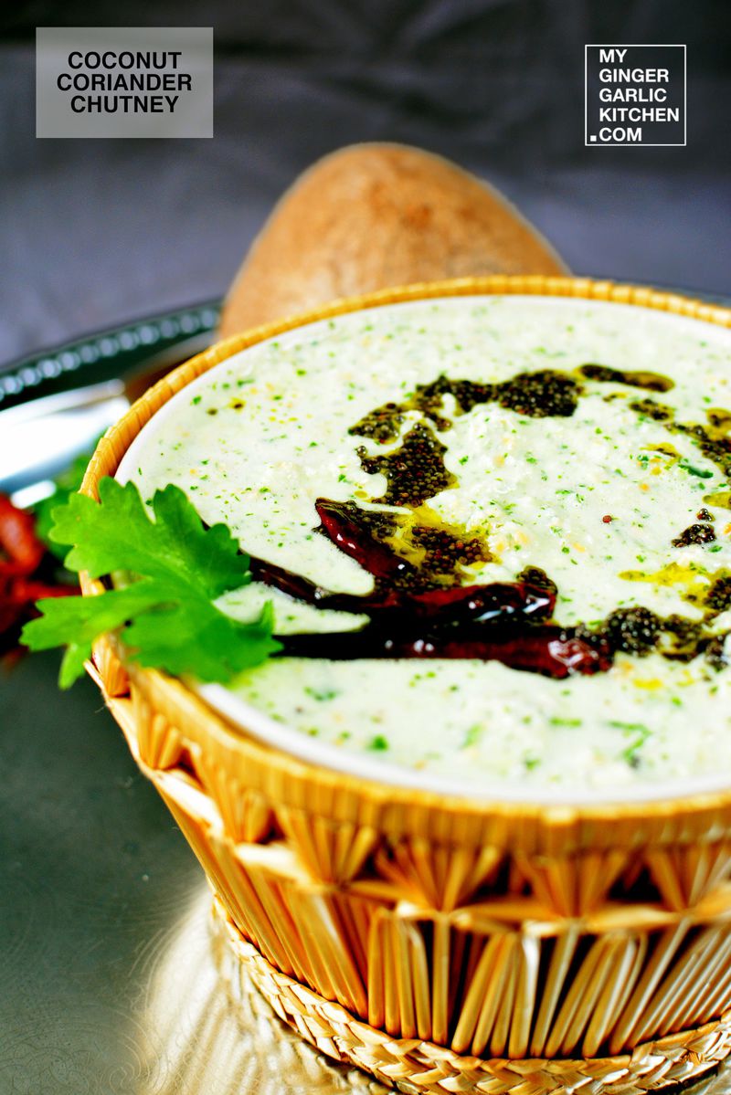 a bowl of coconut coriander chutney with tempering and dried red chilies on a cutting board