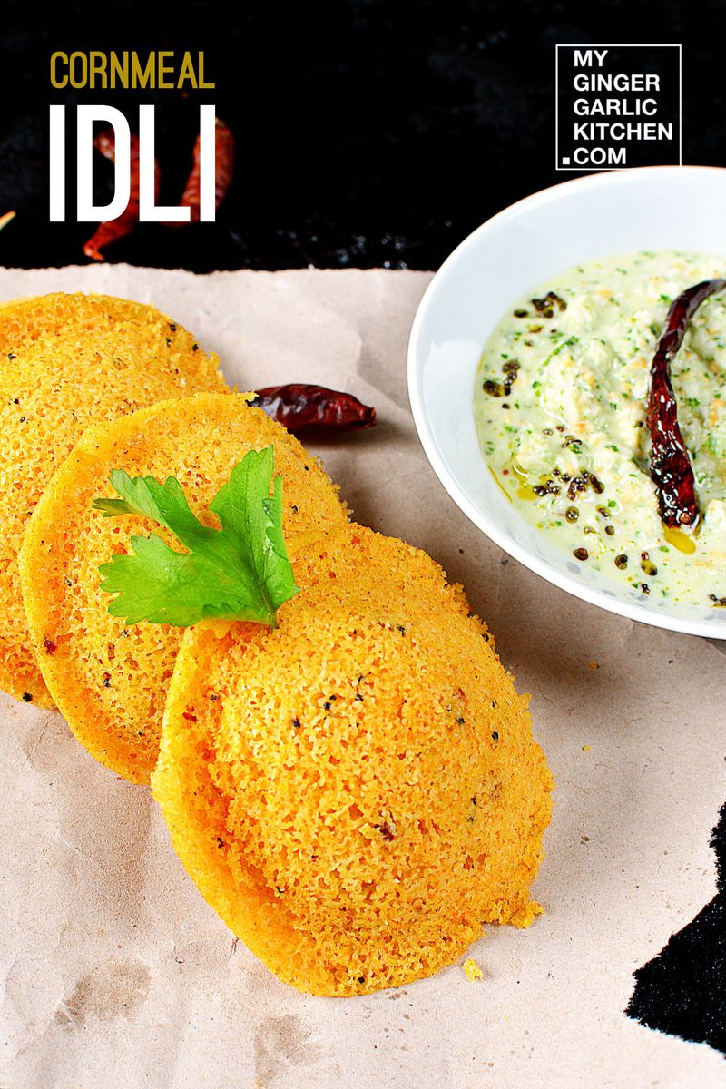 three pieces of cornmeal idli on a plate next to a bowl of chutney