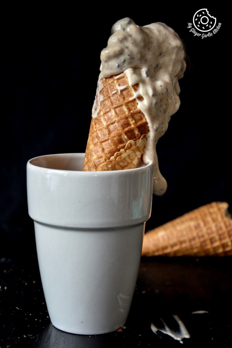 a cone of creamy coconut coffee chocolate chunk ice cream in a cup with a spoon