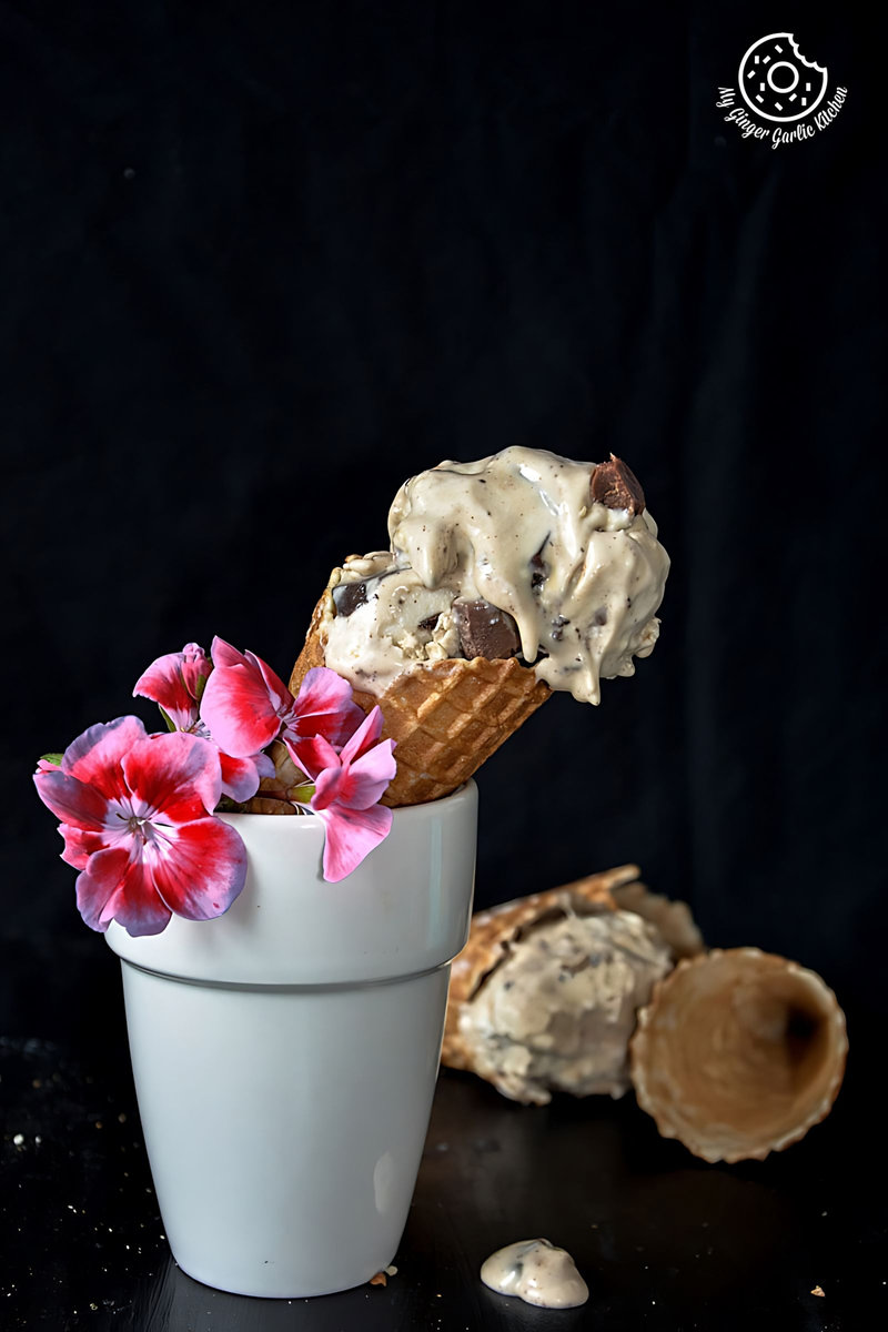 a cup with a creamy coconut coffee chocolate chunk ice cream cone and flowers in it