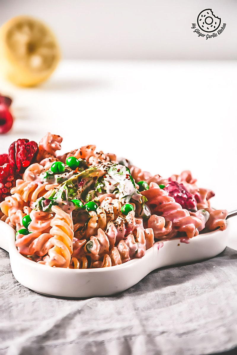 a bowl of creme fraiche raspberry peas pasta and vegetables on a table