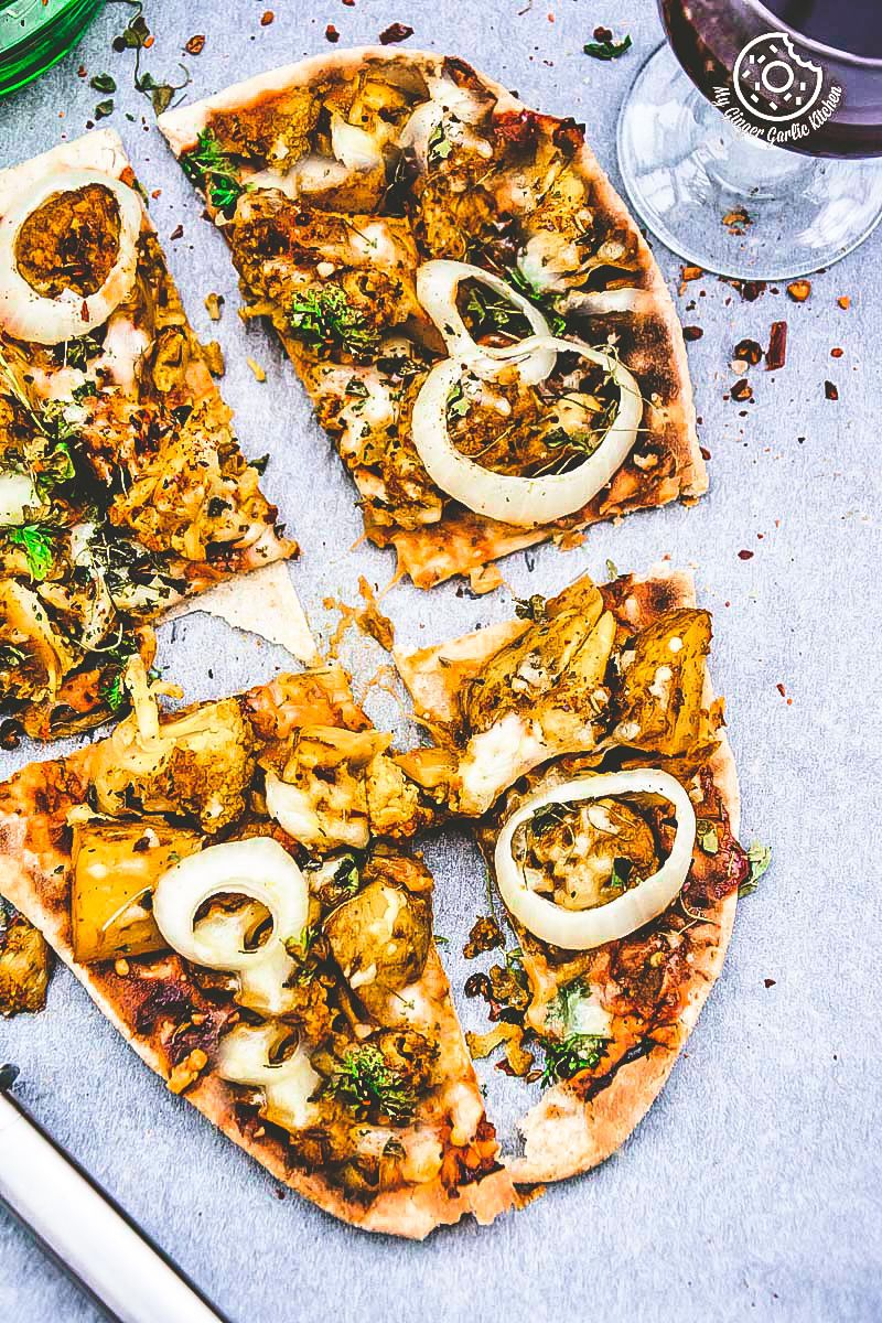 a curried cauliflower topped naan pizza with onions and broccoli on it