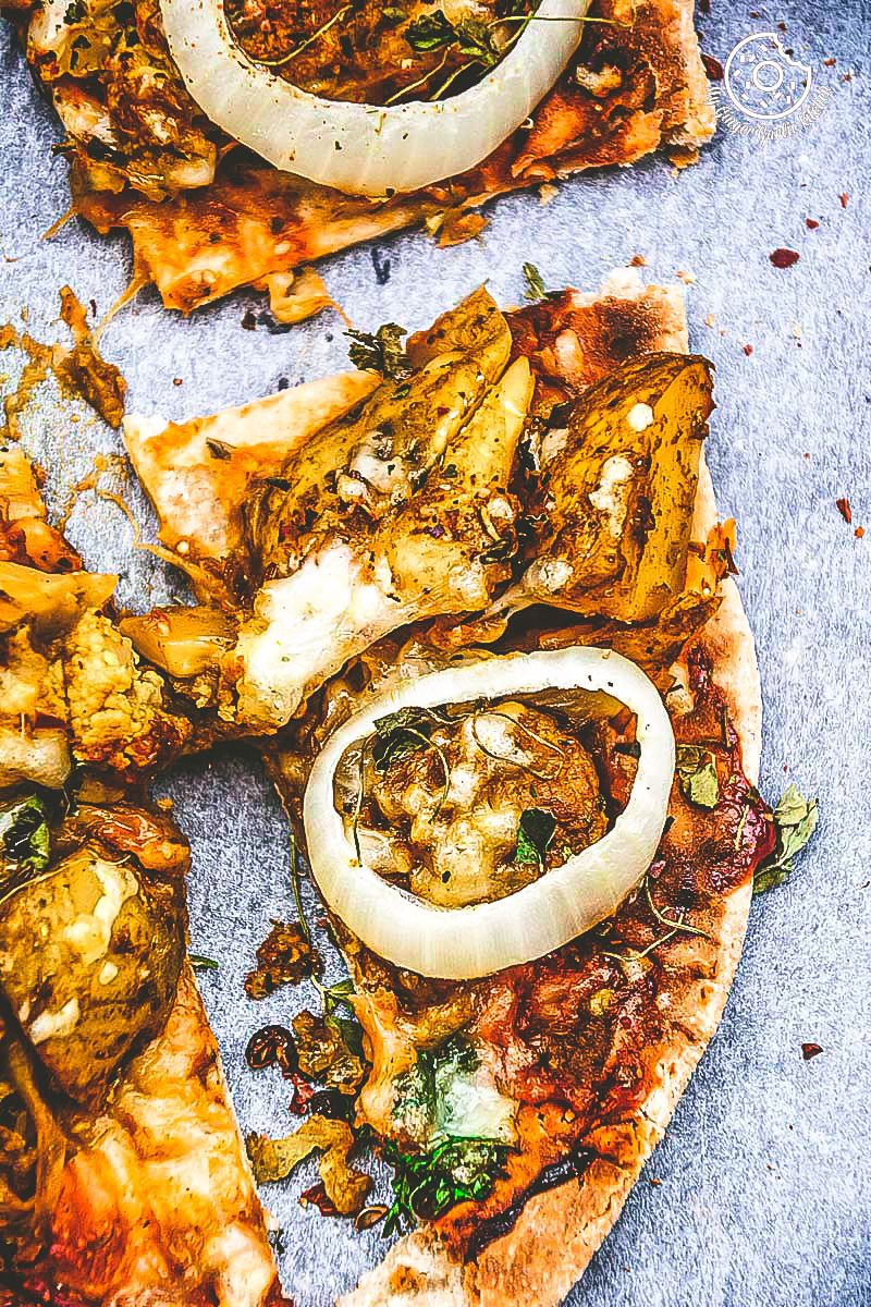 a curried cauliflower topped naan pizza with onions and other toppings on it