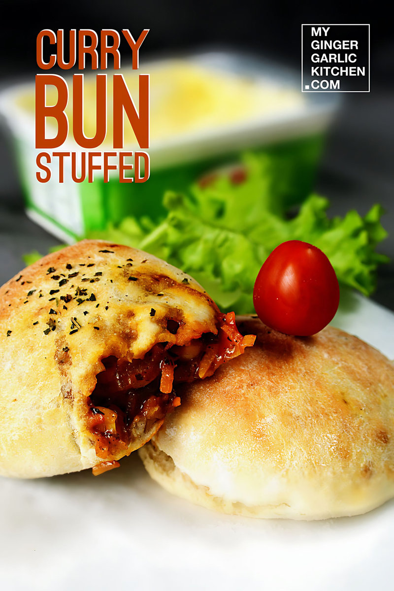 a plate of curry stuffed bun with a tomato on it