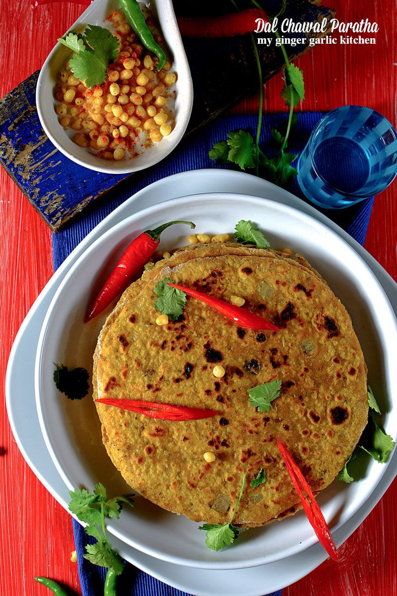 a plate of dal chawal paratha with sliced red chili on it