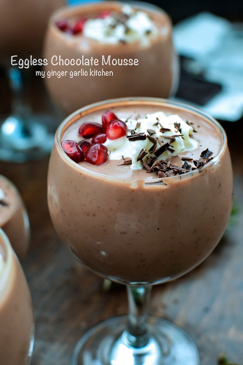 eggless chocolate mousse with whipped cream and pomegranate garnish in a glass