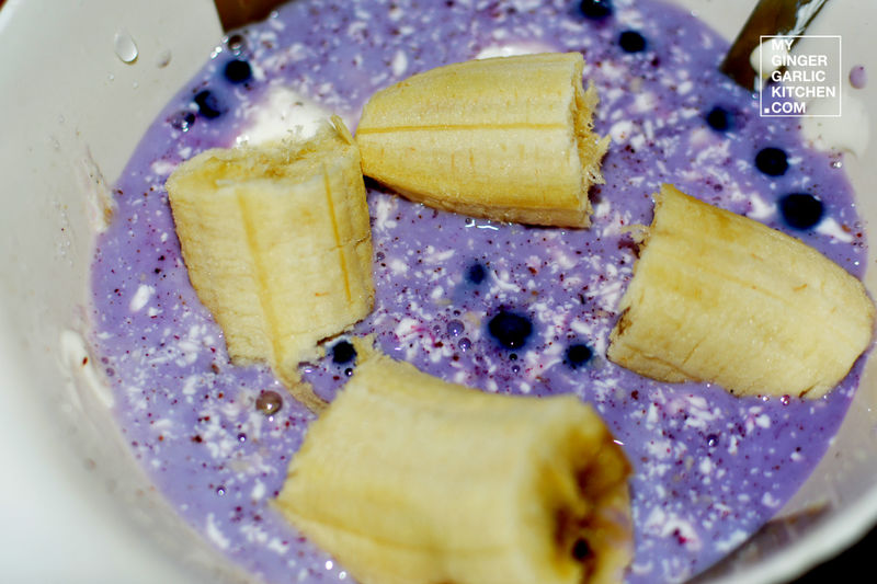 a bowl of blueberry and banana soup with a spoon