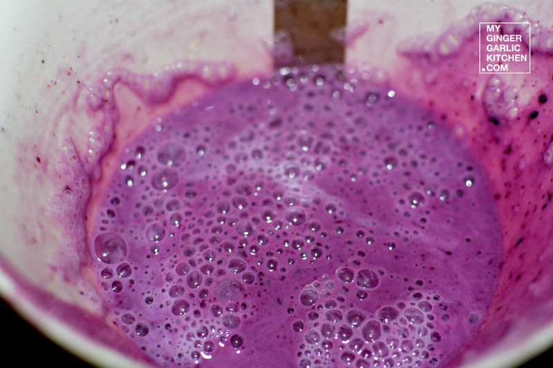 purple liquid in a blender with a wooden spoon