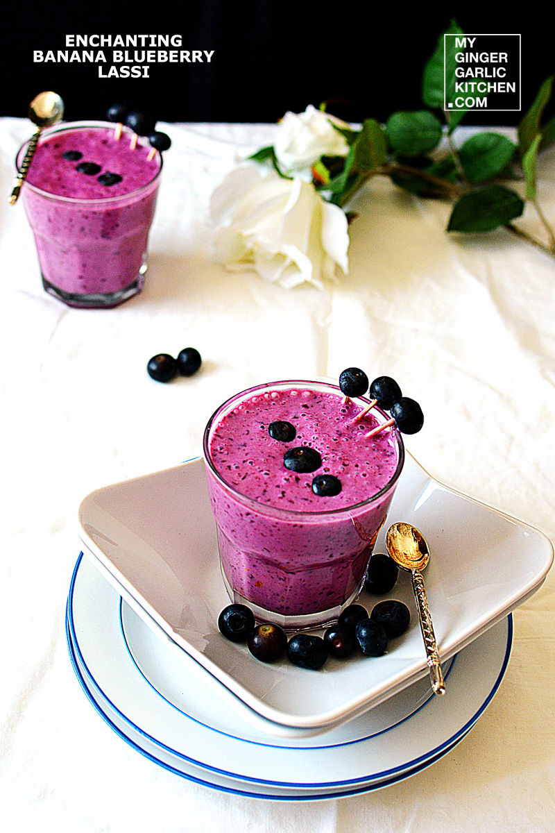 a banana blueberry lassi topped with blueberries with one more glass in background