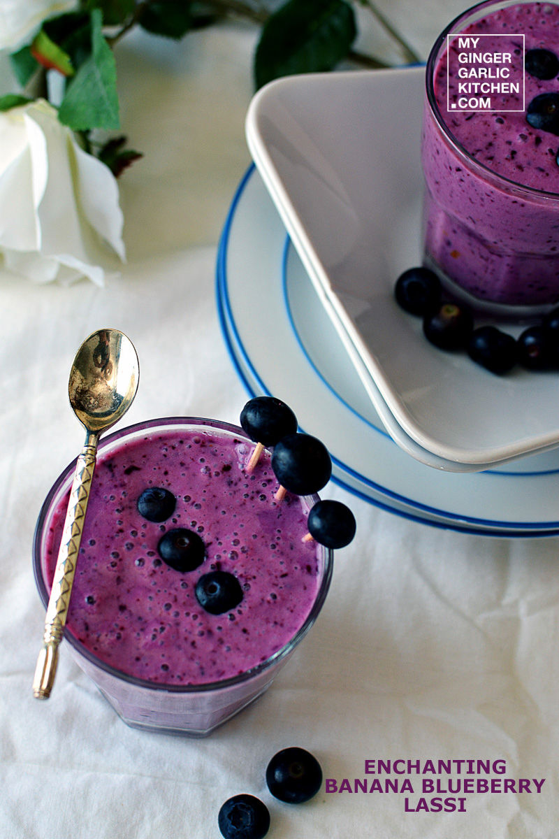 a banana blueberry lassi aka blueberry smoothie in a glass with a spoon