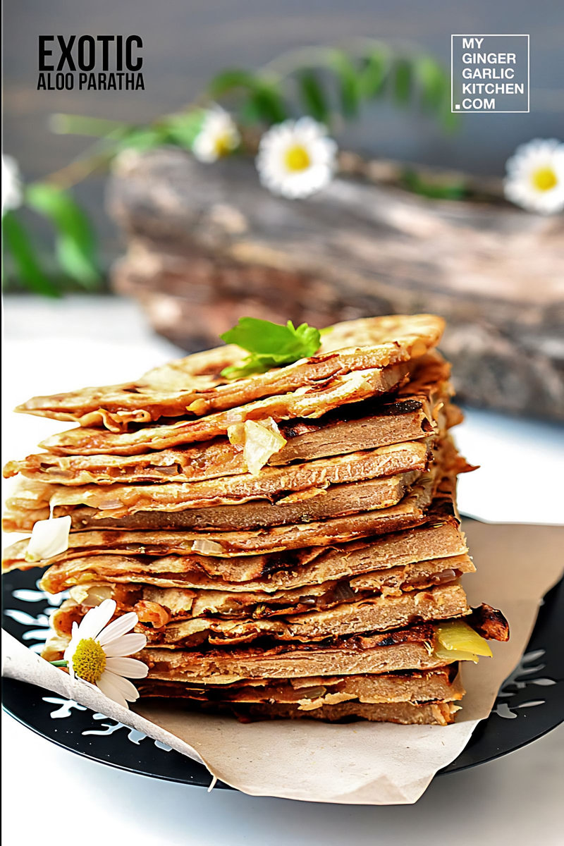a stack of aloo paratha pieces on a plate with a flower