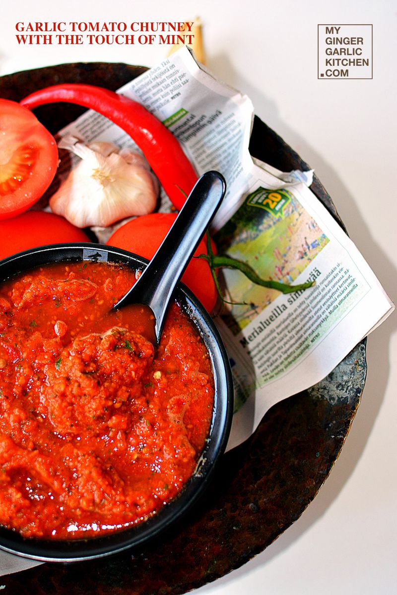 bowl of garlic tomato chutney with a spoon and a newspaper on a plate