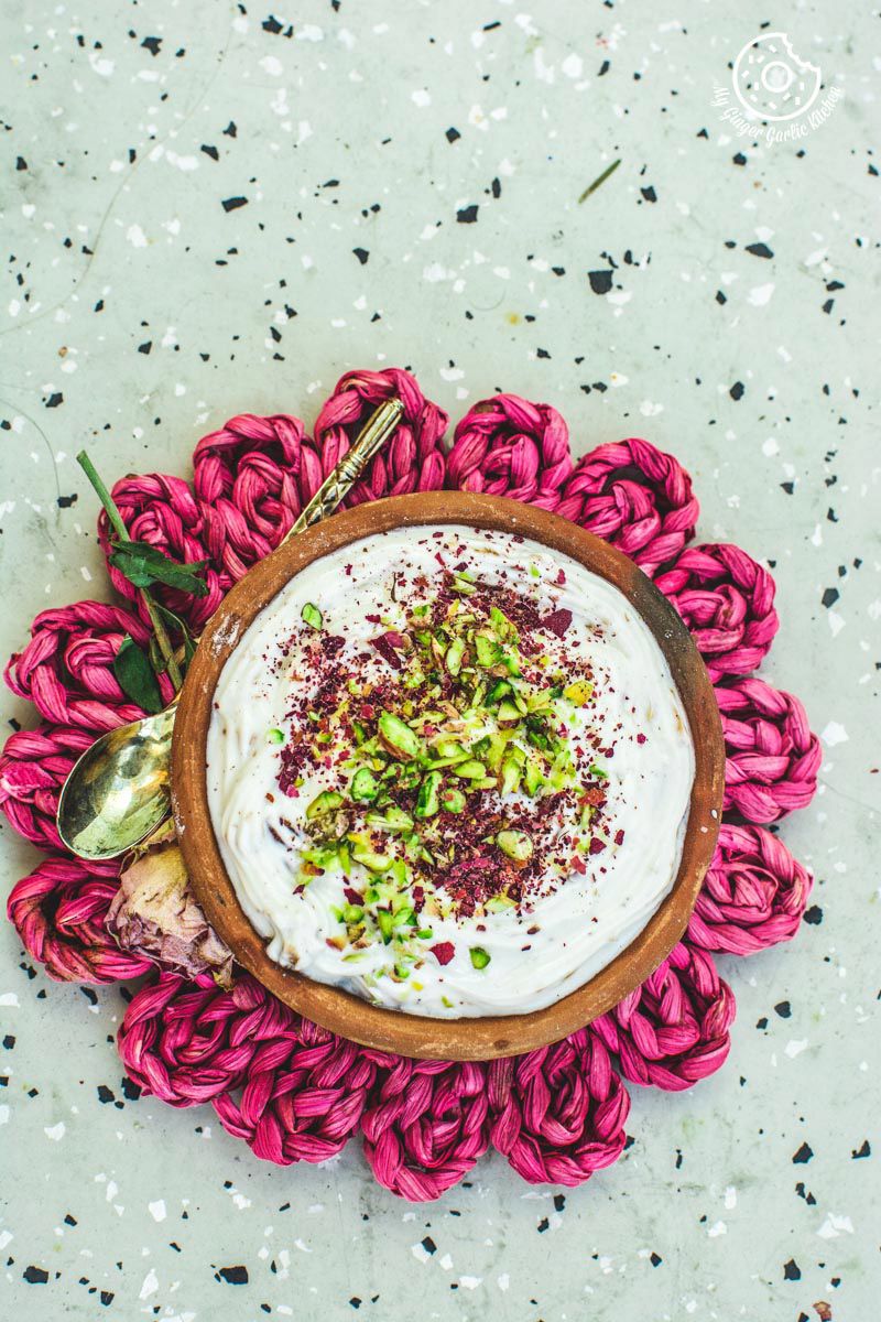 a bowl of rose shrikhand with a spoon rest on a pink mat