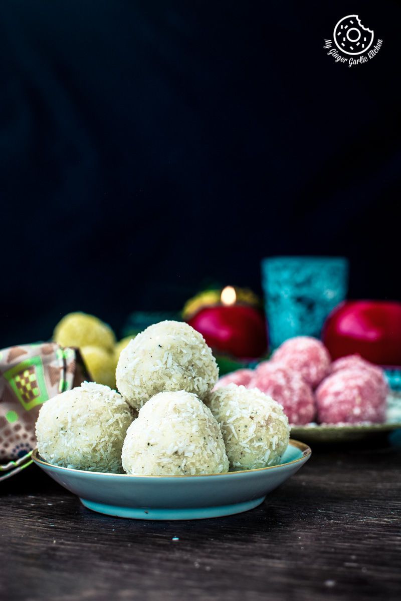 a plate of coconut instant coconut ladoo sitting on a table with saffron instant coconut ladoo and rose instant coconut ladoo