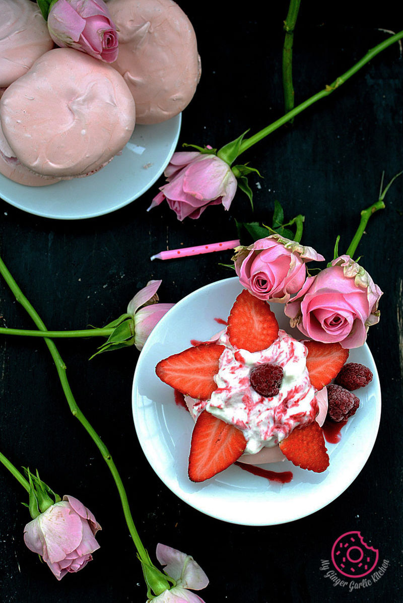 a plate of mini beryy pavlova with strawberries and pink roses