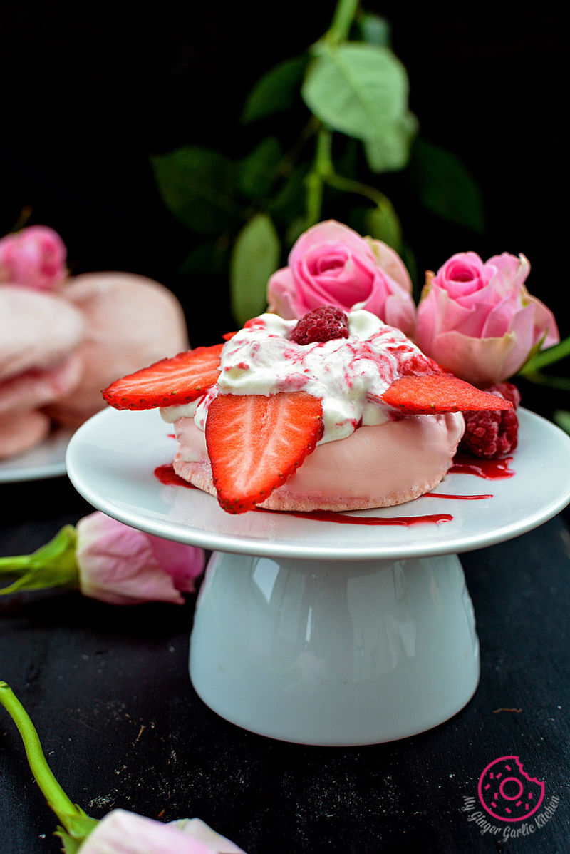 a mini beryy pavlova with strawberries and whipped cream on a plate