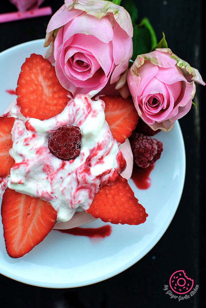 a plate of mini beryy pavlova and strawberries with a pink rose flower