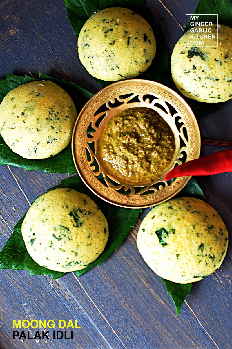 a tray of moong dal palak idli with a bowl of chutney on it