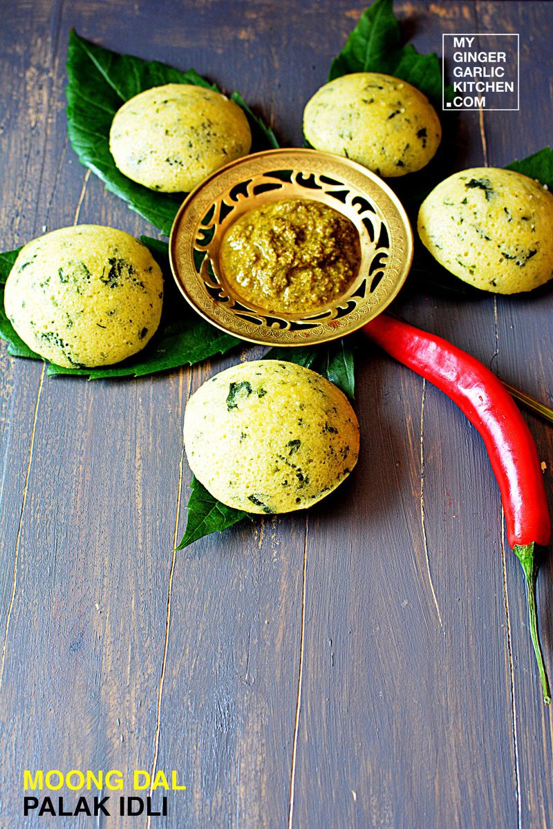 a tray of moong dal palak idli with a chili and some leaves