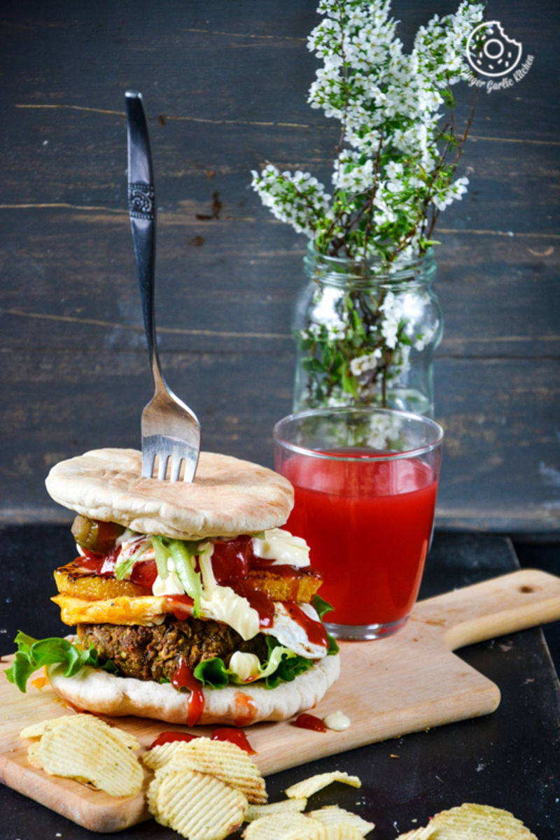 a mung bean pita burger with caramelised oranges and mango chutney with a fork and chips on a cutting board