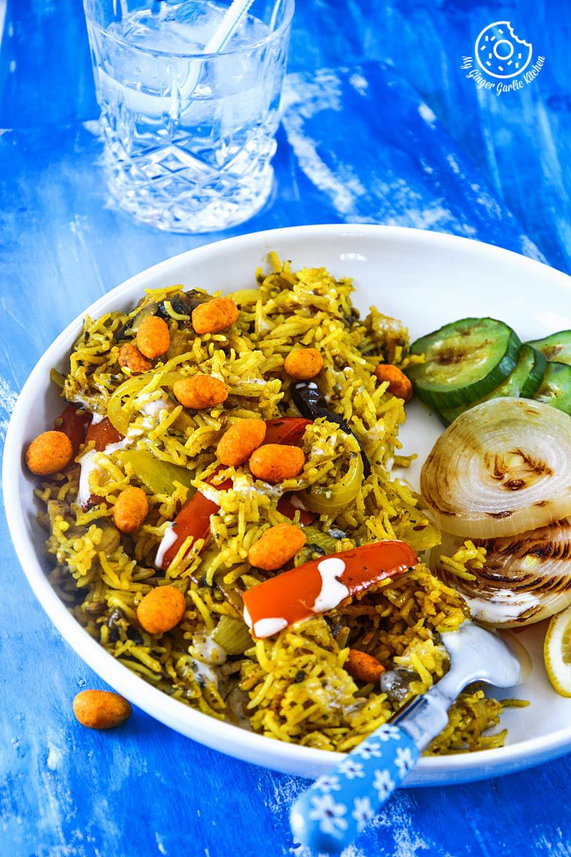 a plate of mushroom pepper pulao with grilled veggies and honey mustard yogurt on a blue table