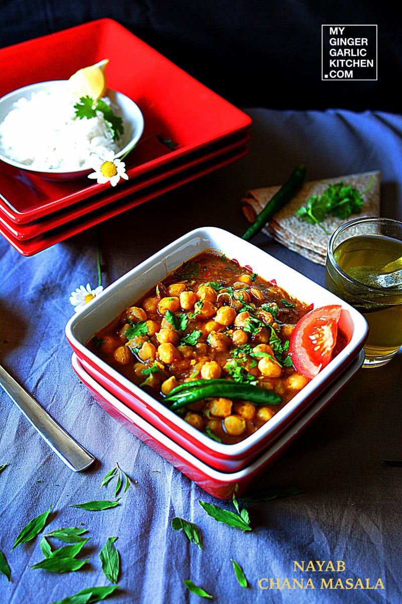 a bowl of chana masala curry on a table with a plate of rice